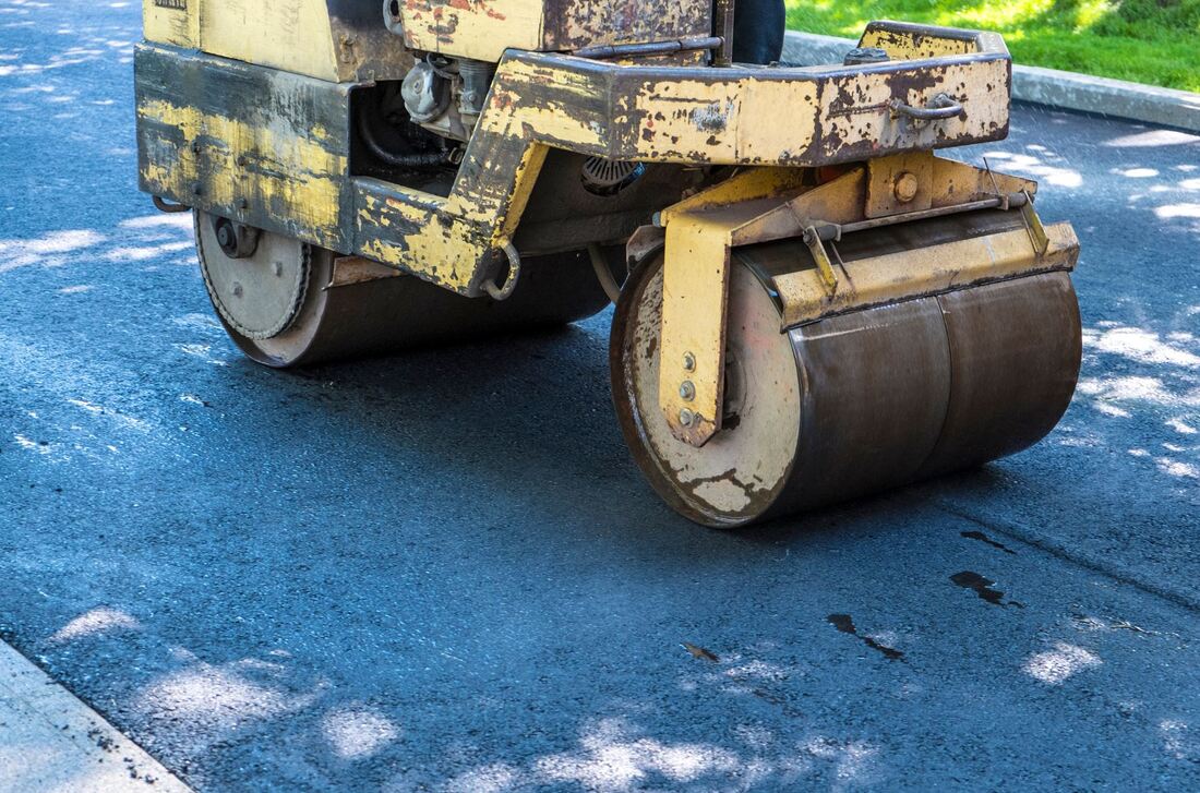 Asphalt paving machine rolling over a driveway