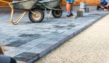 Laying gray pavers on a driveway that is being constructed