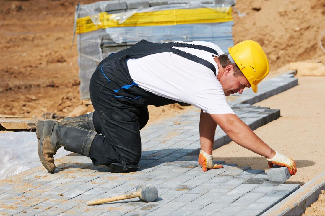 Worker placing bricks in a patterned formation for a new sidewalk